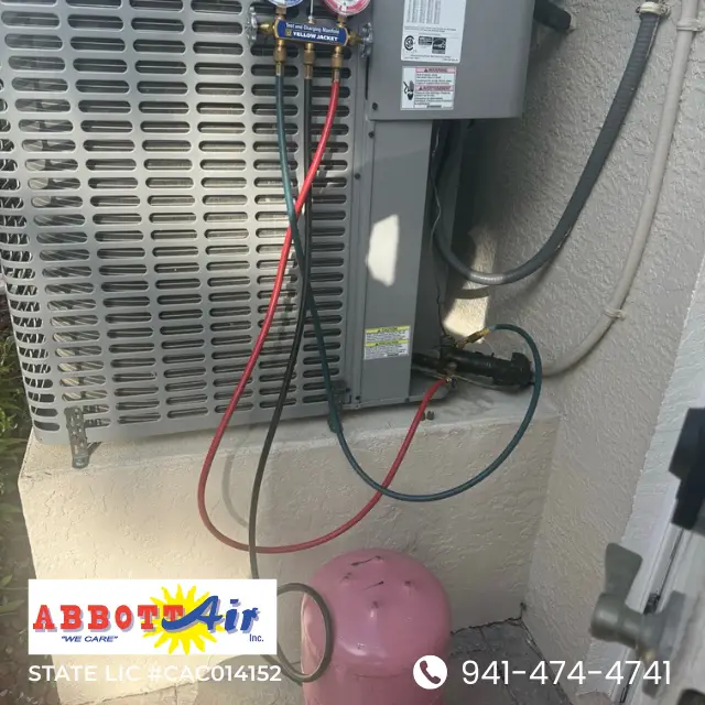 Air conditioning unit connected with red, black, and blue hoses for refrigerant filling service.
