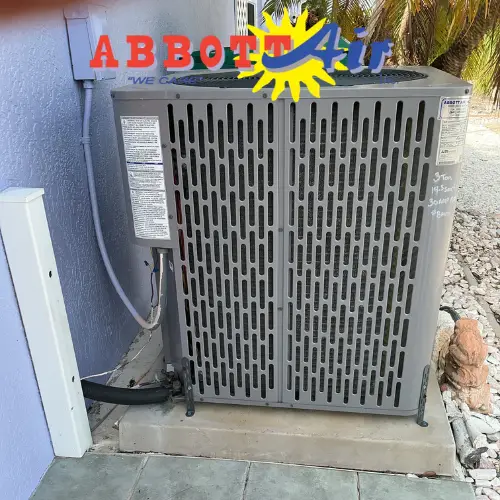 Gray Abbott Air outdoor AC unit installed on a concrete slab beside a house wall.