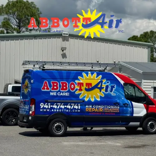 A blue and red Abbott Air Inc. van parked outside a metal building, featuring a yellow sun logo and text advertising air conditioning repair, replacement, and maintenance with contact number 941-474-4741 and website www.abbottac.com.