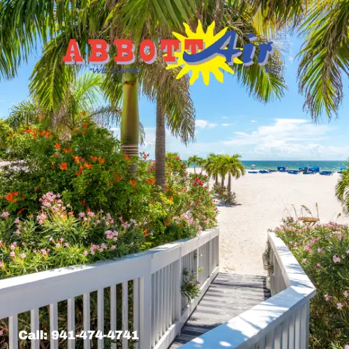 Wooden walkway with white railings leads through lush tropical plants and palm trees to a sunny beach with blue sky and ocean, featuring the Abbott Air logo and a phone number to call.