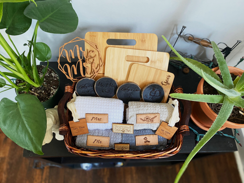 Forged One Two Wedding Season Gift basket that has laser cut customized Mr. and Mrs. wooden coasters, tea towels, and cutting boards.