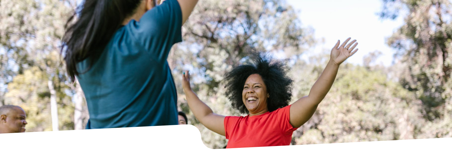 Photo of two women smiling with their arms raised in active wear.