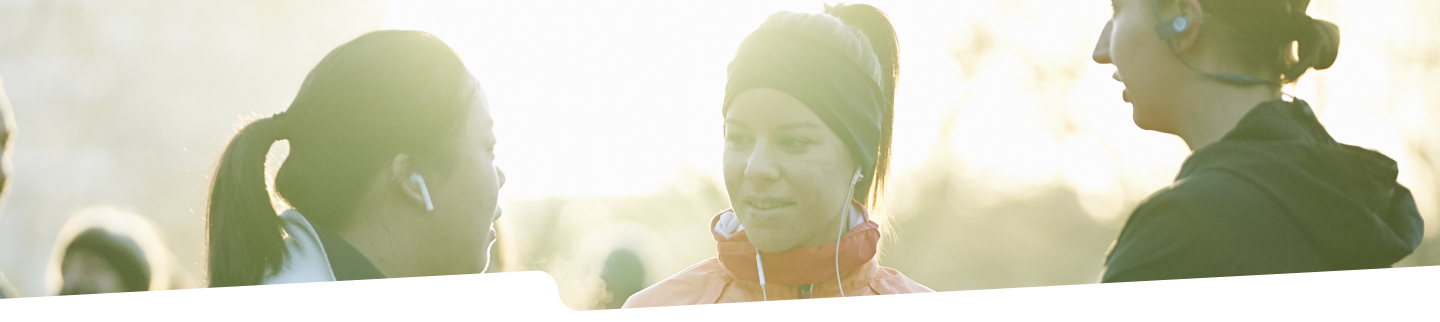 Photograph of 3 women in winter activewear talking in a park.