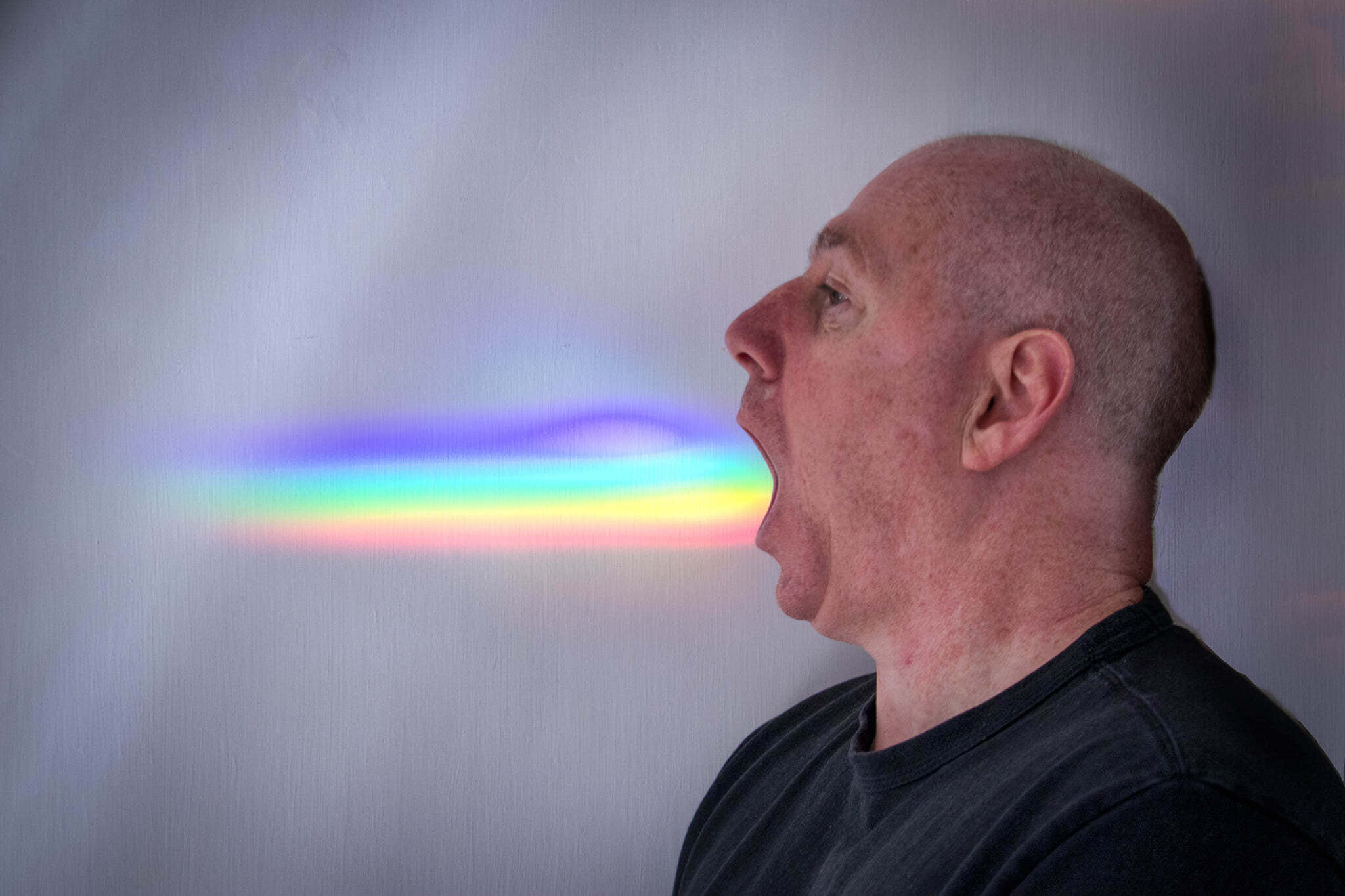 Picture of a man opening his mouth with a rainbow coming out