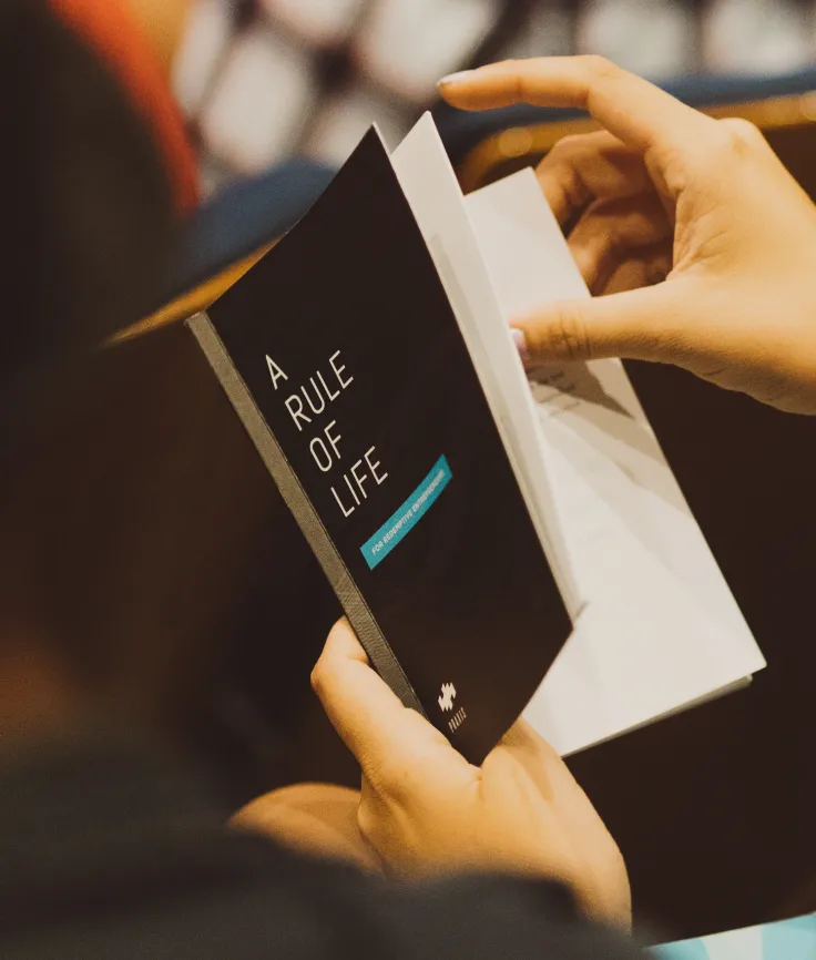Close-up of a person flipping through the book, "A Rule of Life"