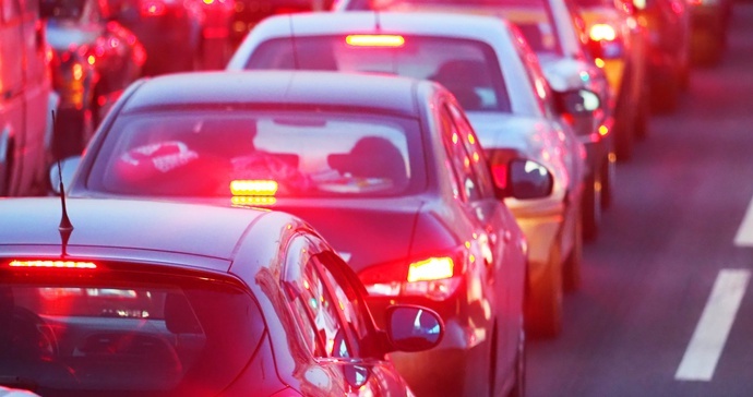 Cars queued nose to tail in traffic at night, brake lights lit