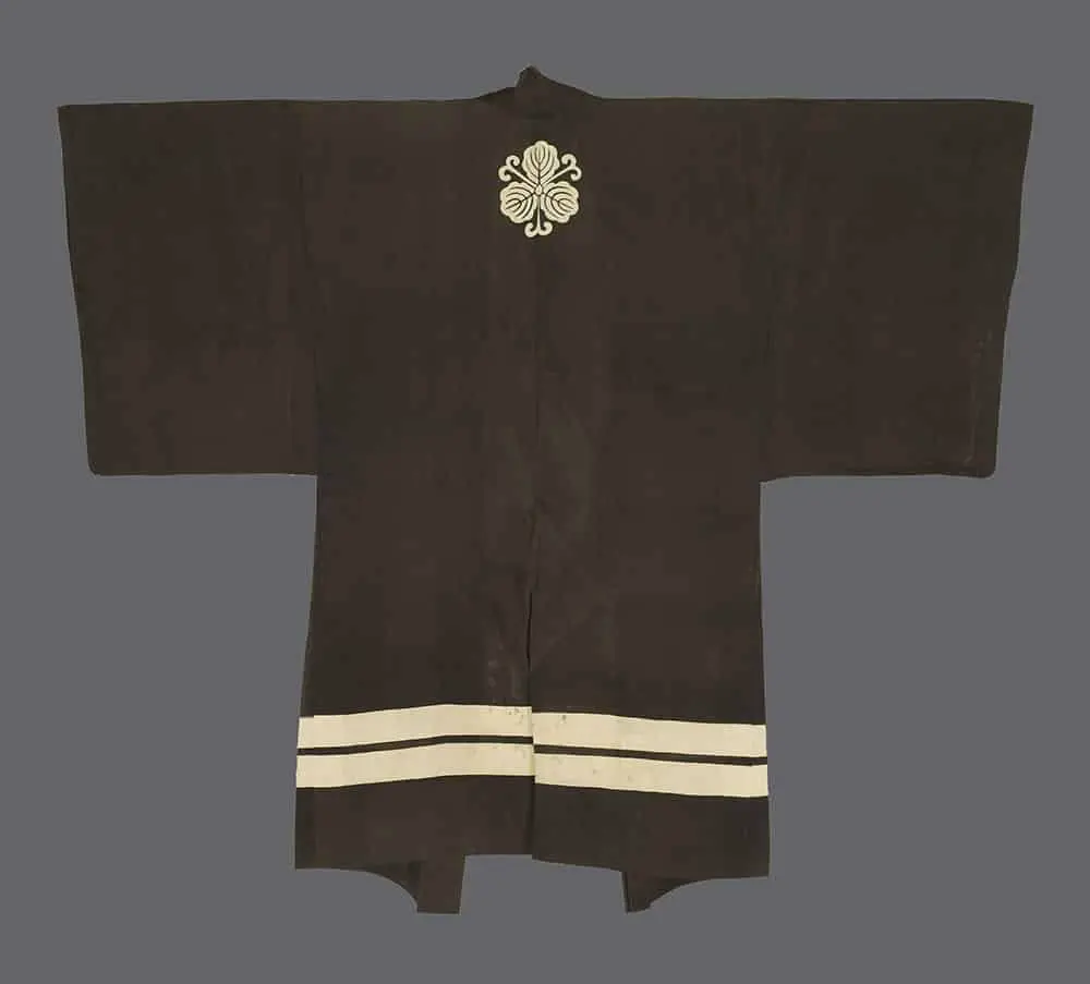 Meiji silk gauze garment with a prominent white kiku‑ or kiri‑style mon in bold geometric curves on a dark ground, used in Kyogen and Shishimai performance