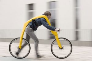 A man riding a bike with a large yellow object on it's back