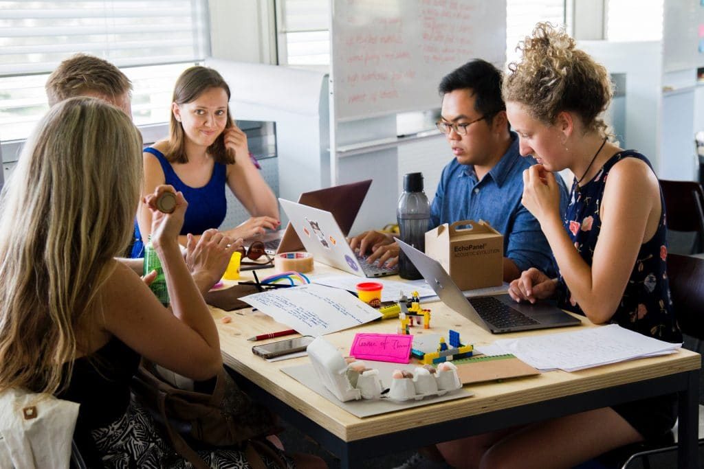 A group of people sitting around a table working on laptops