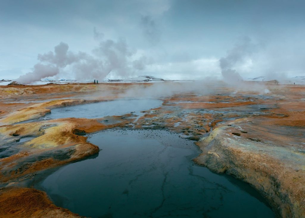 A body of water surrounded by rocks and steam