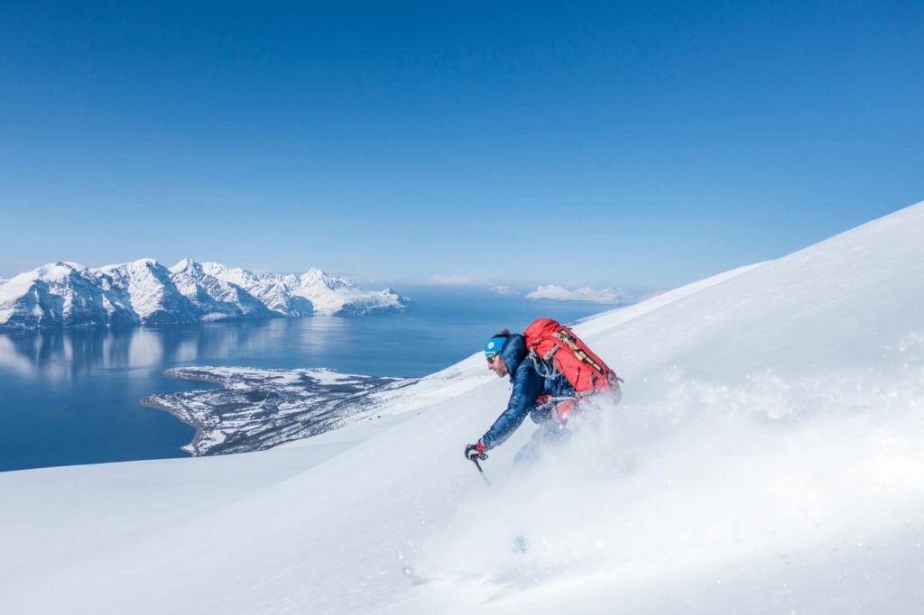 A man riding skis down the side of a snow covered slope