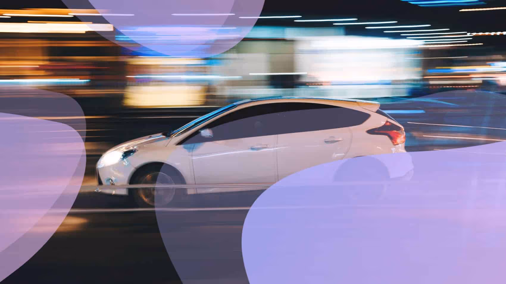 A white car driving down a street at night