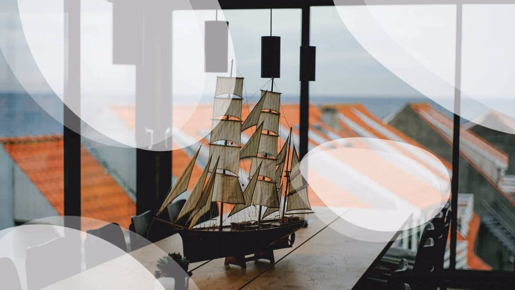 A model of a sailboat on a table in front of a window