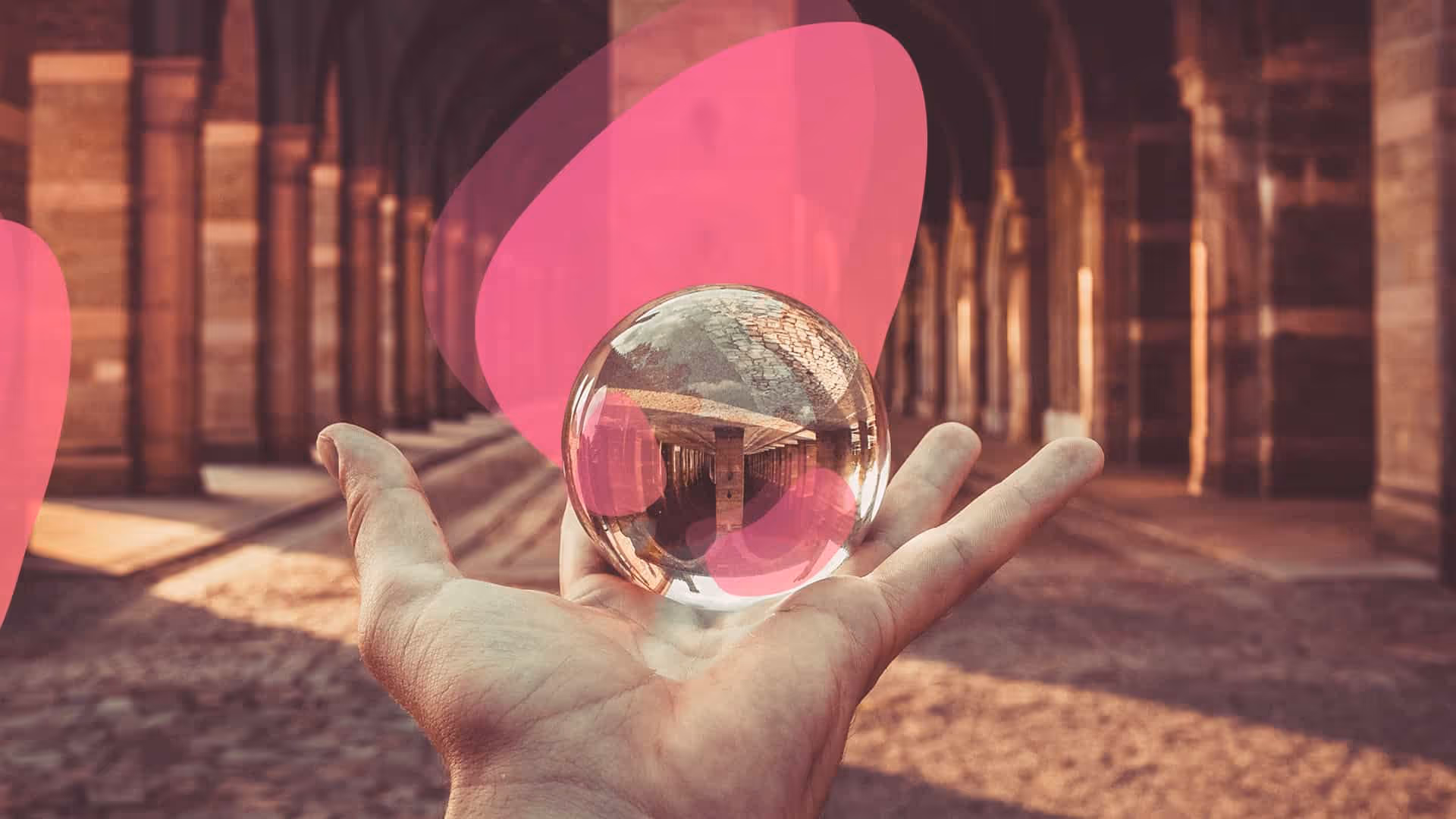 Une main tenant une boule de verre devant un bâtiment