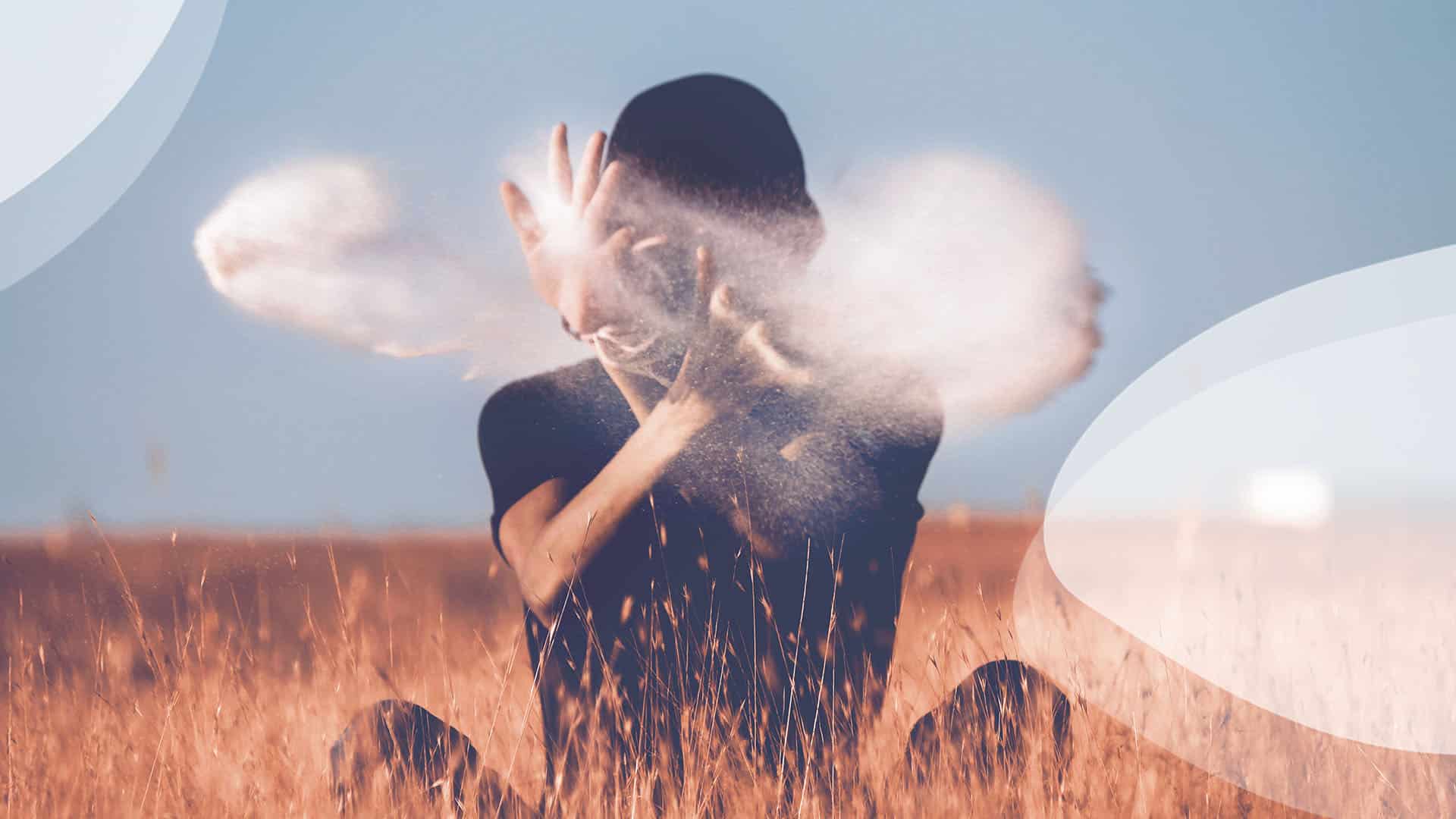 Une personne assise dans un champ les mains en l'air