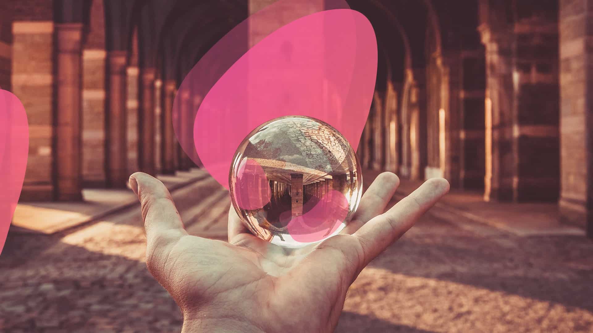 A hand holding a glass ball in front of a building