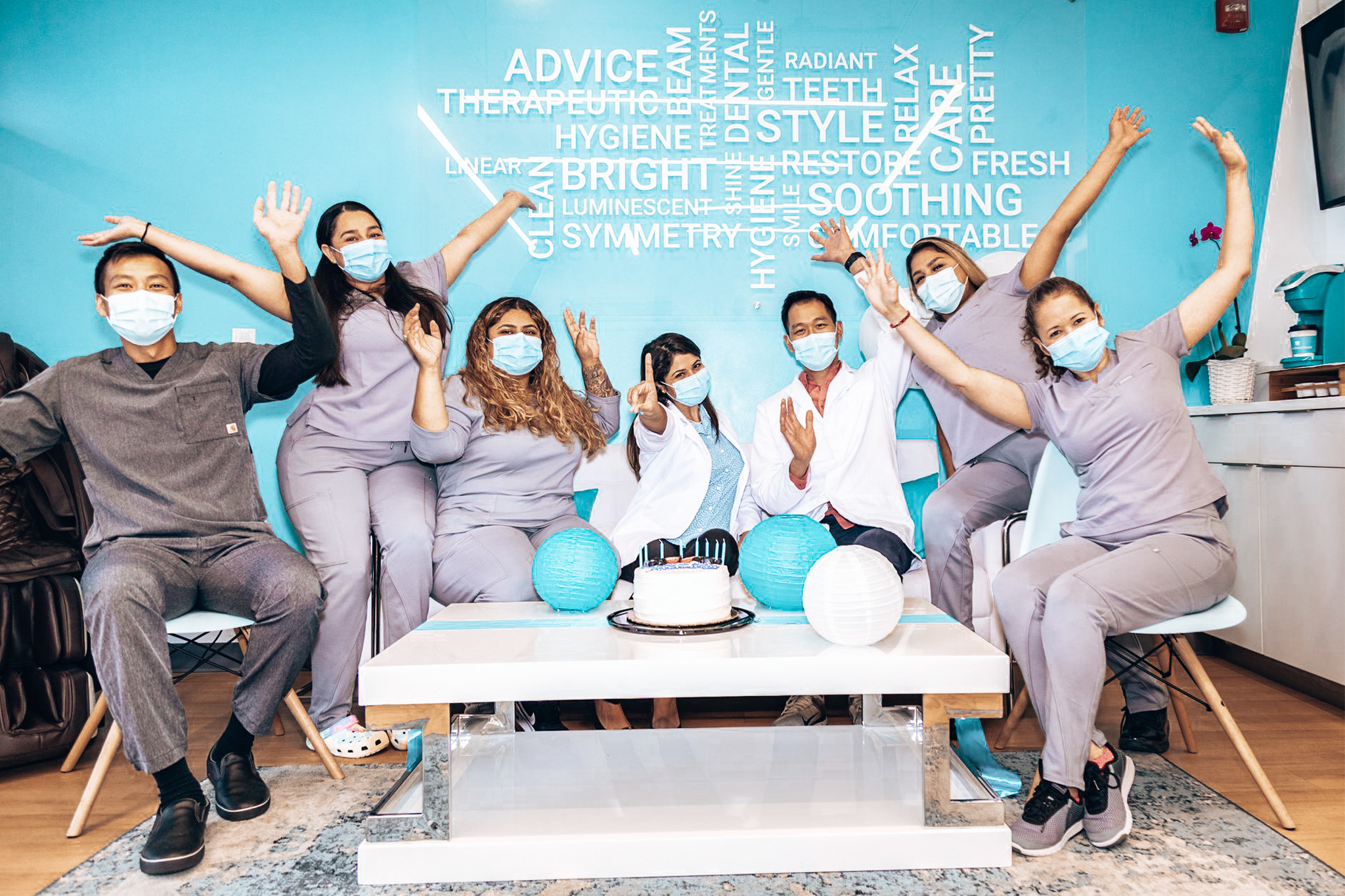 8 Trident Smiles Dental specialists sitting in the waiting room of the Sunnyvale location and waving excitedly at the camera