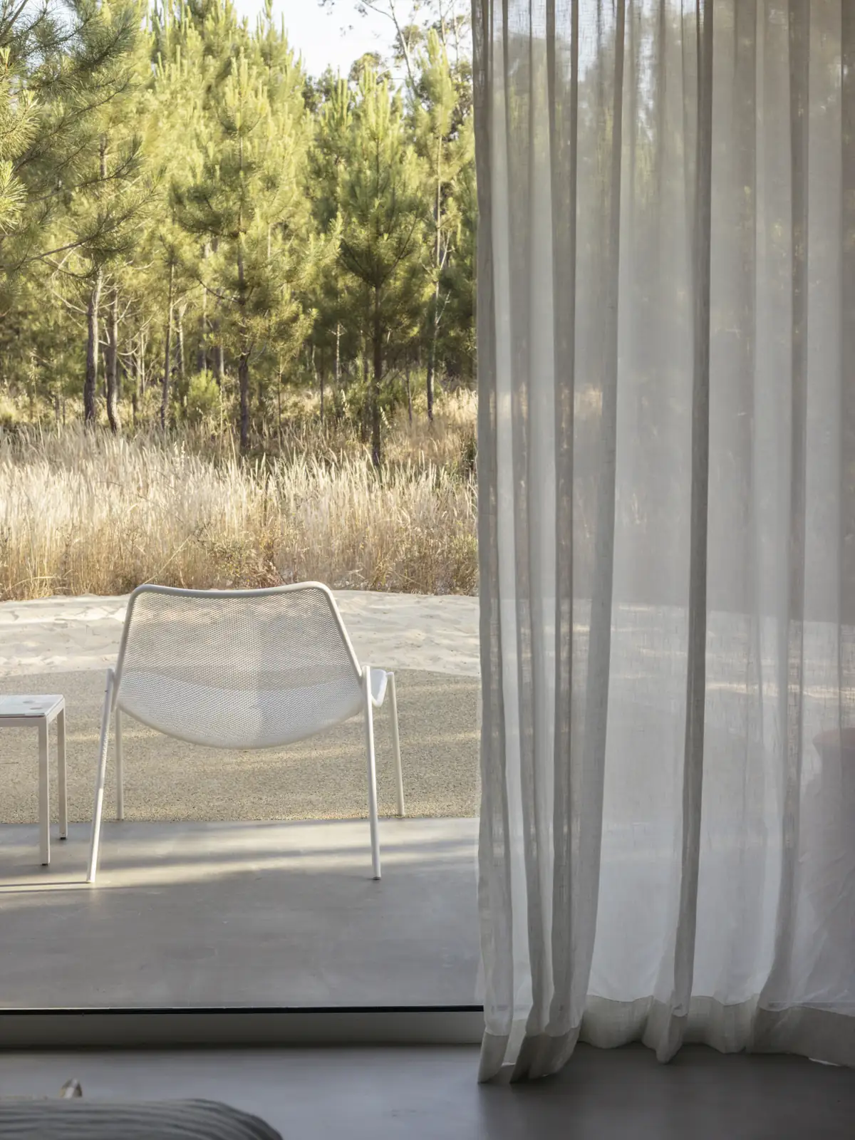 Cabana window overlooking the terrace and the woods ta Spatia Comporta, a five-star hotel retreat.