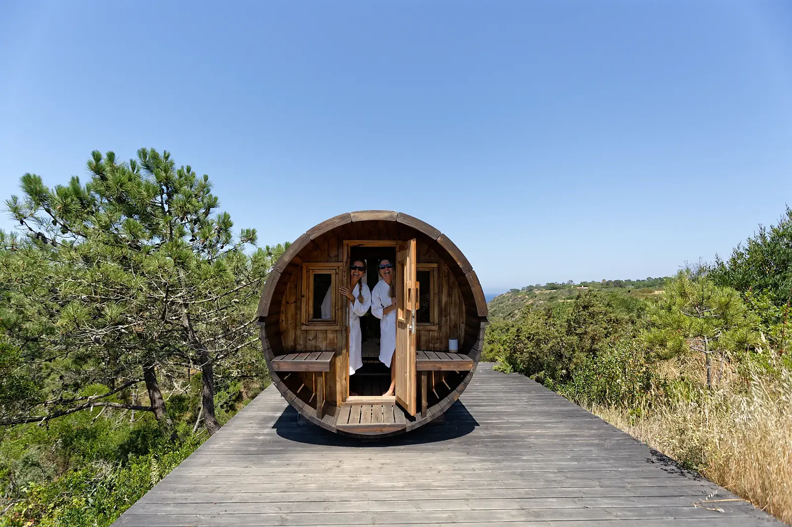 Joana and Sofia from JO&SO in the wood-burning barrel sauna at Amaria, facing the Atlantic