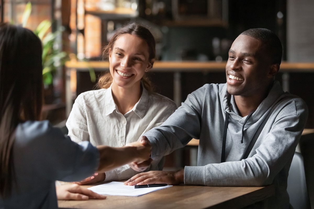 A man shaking hands with an AC Abstract employee, while sitting next to a woman.