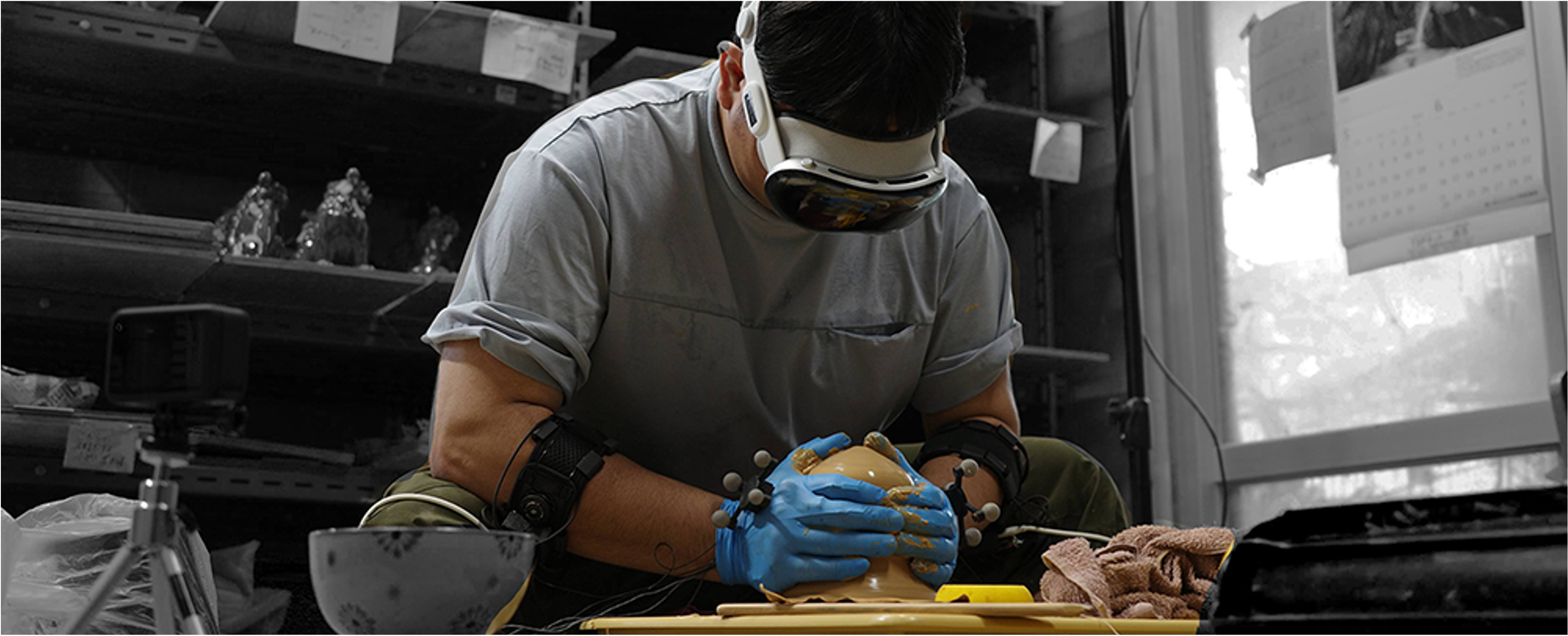 A researcher recording pottery-making using a headset and wearable hand and arm sensors