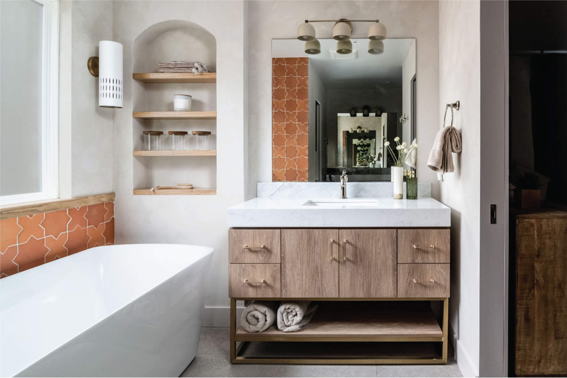 Modern bathroom with wood vanity, white tub, and patterned tile accents
