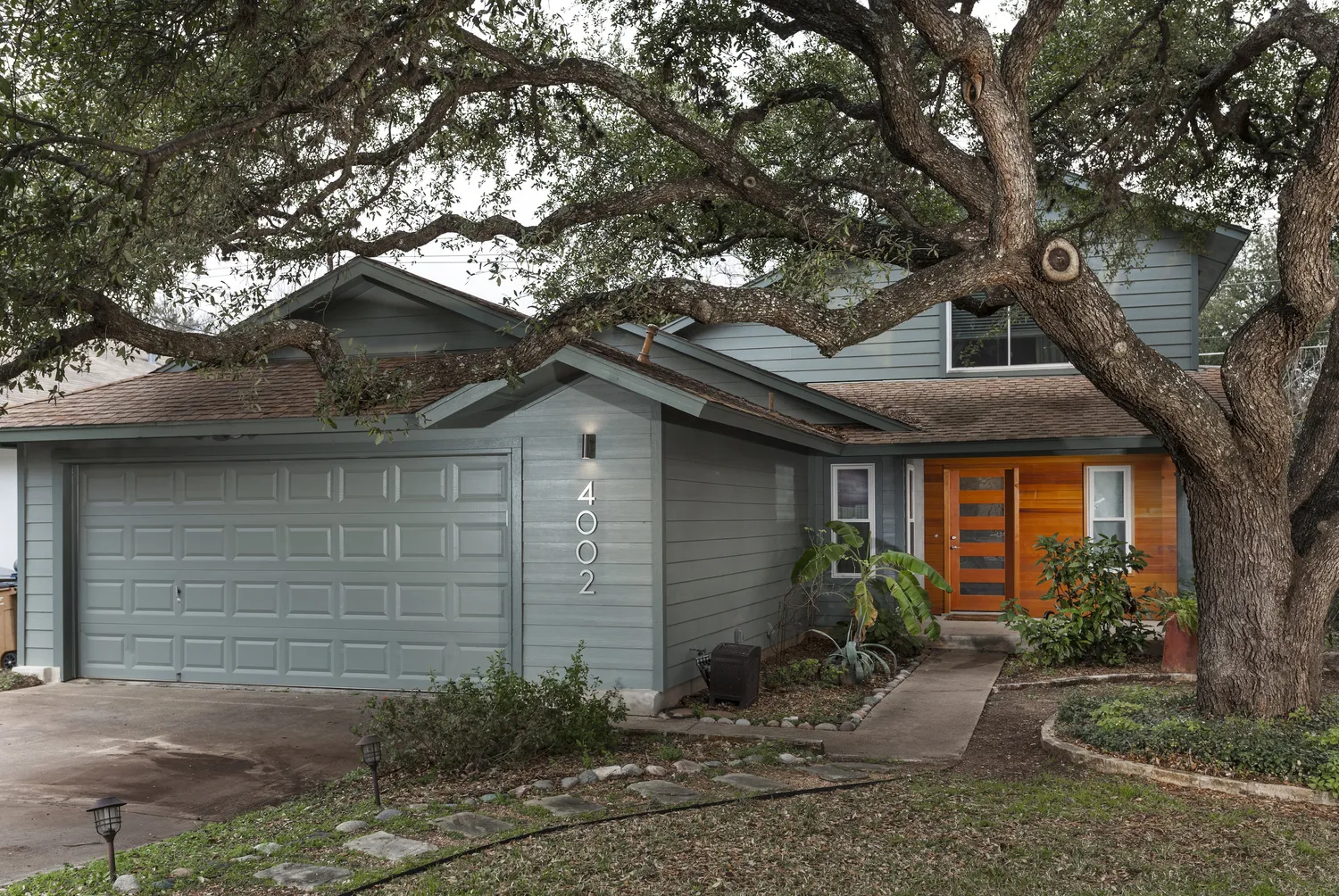 Two-Story House With Blue-Grey Siding, Two-Car Garage, and Wooden Double Doors