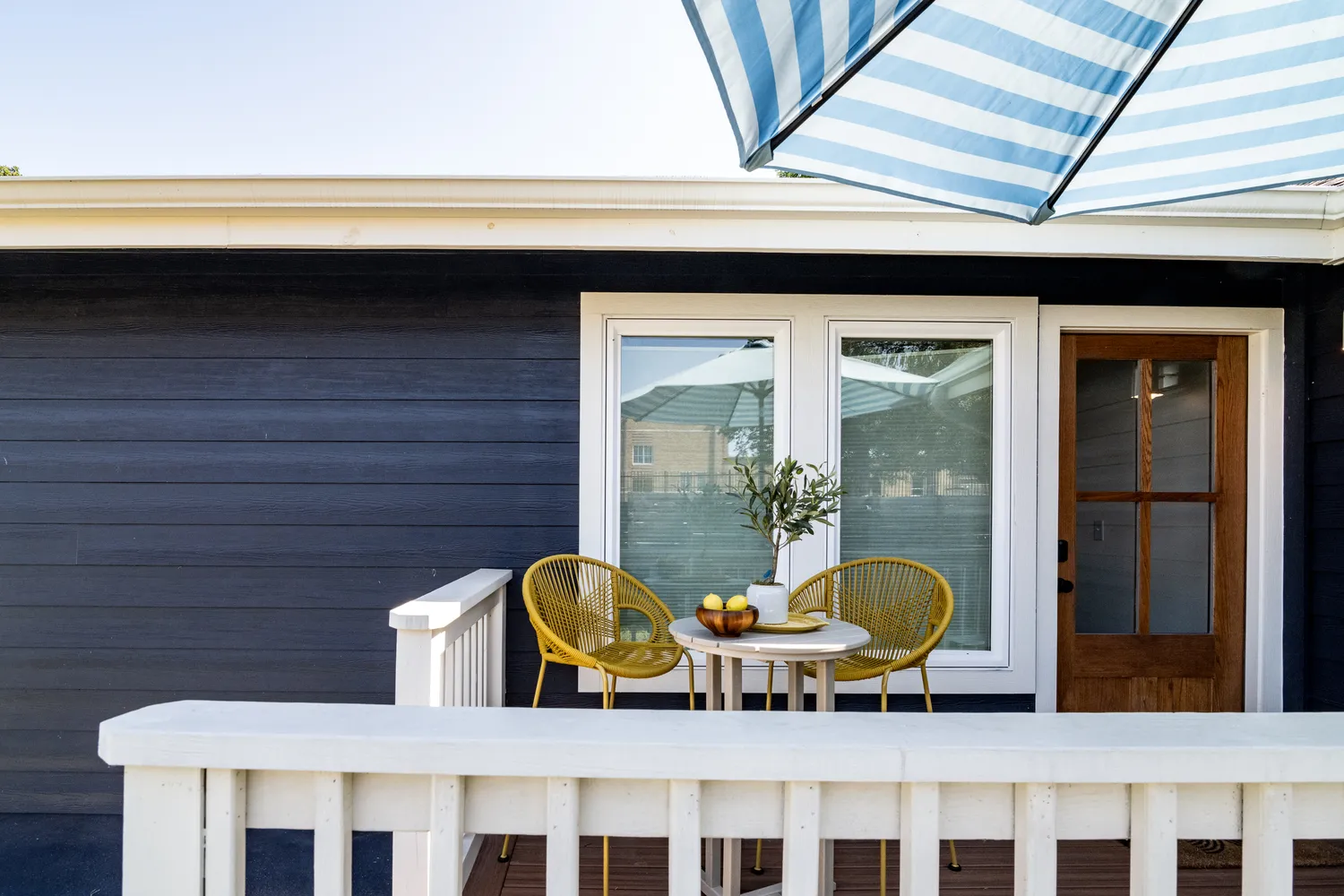 Cozy Outdoor Patio with Yellow Chairs and Striped Umbrella