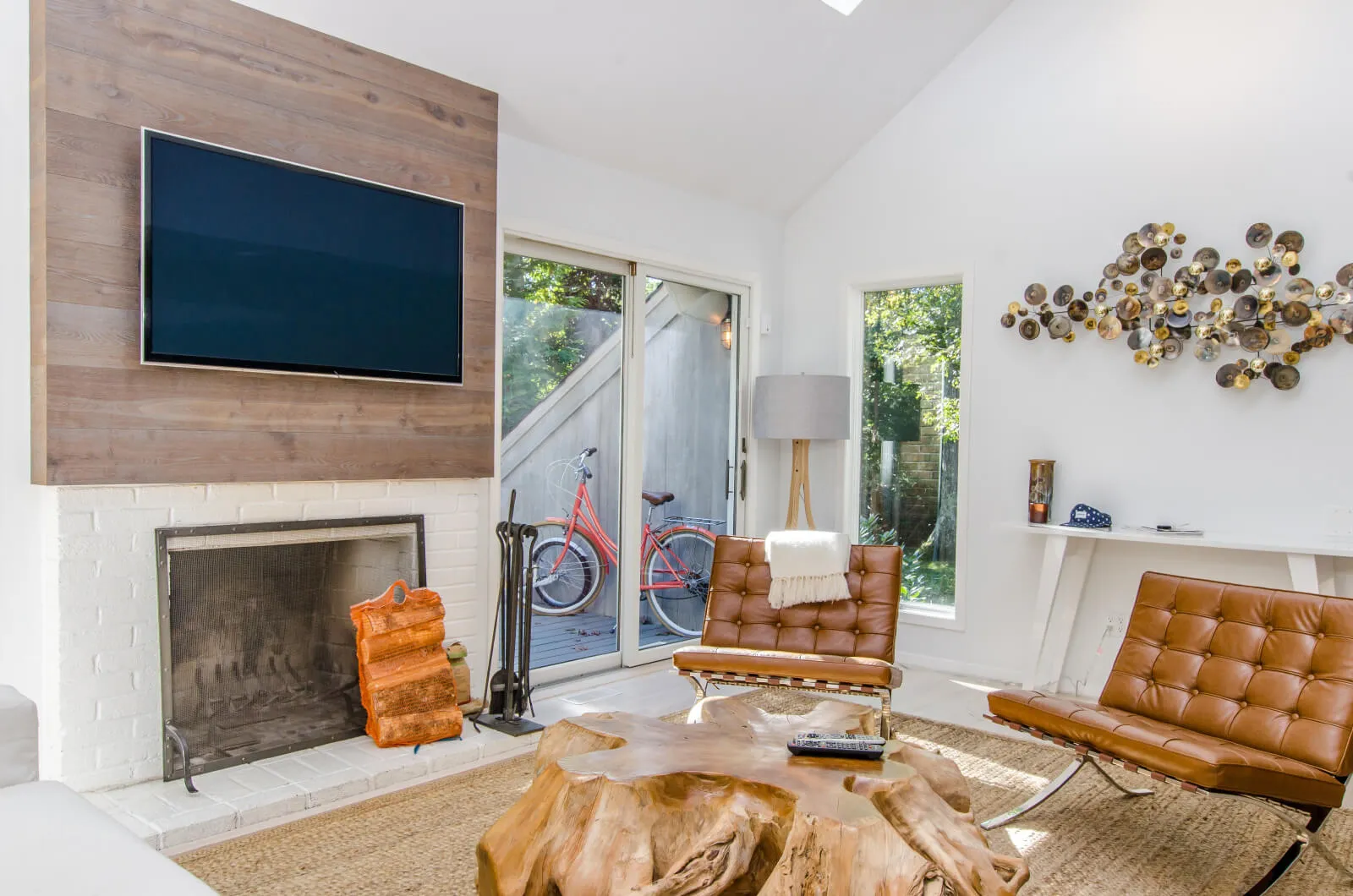 Bright living room with leather chairs, wooden table, fireplace, and wall-mounted TV