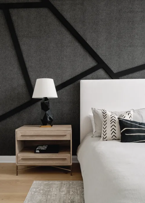Wooden nightstand, partial bed view and a grey wall with black line details