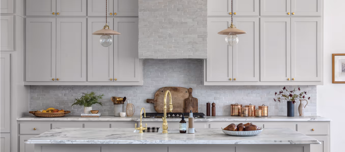 Large kitchen with light grey cabinets, a gold faucet, and pendant lighting 