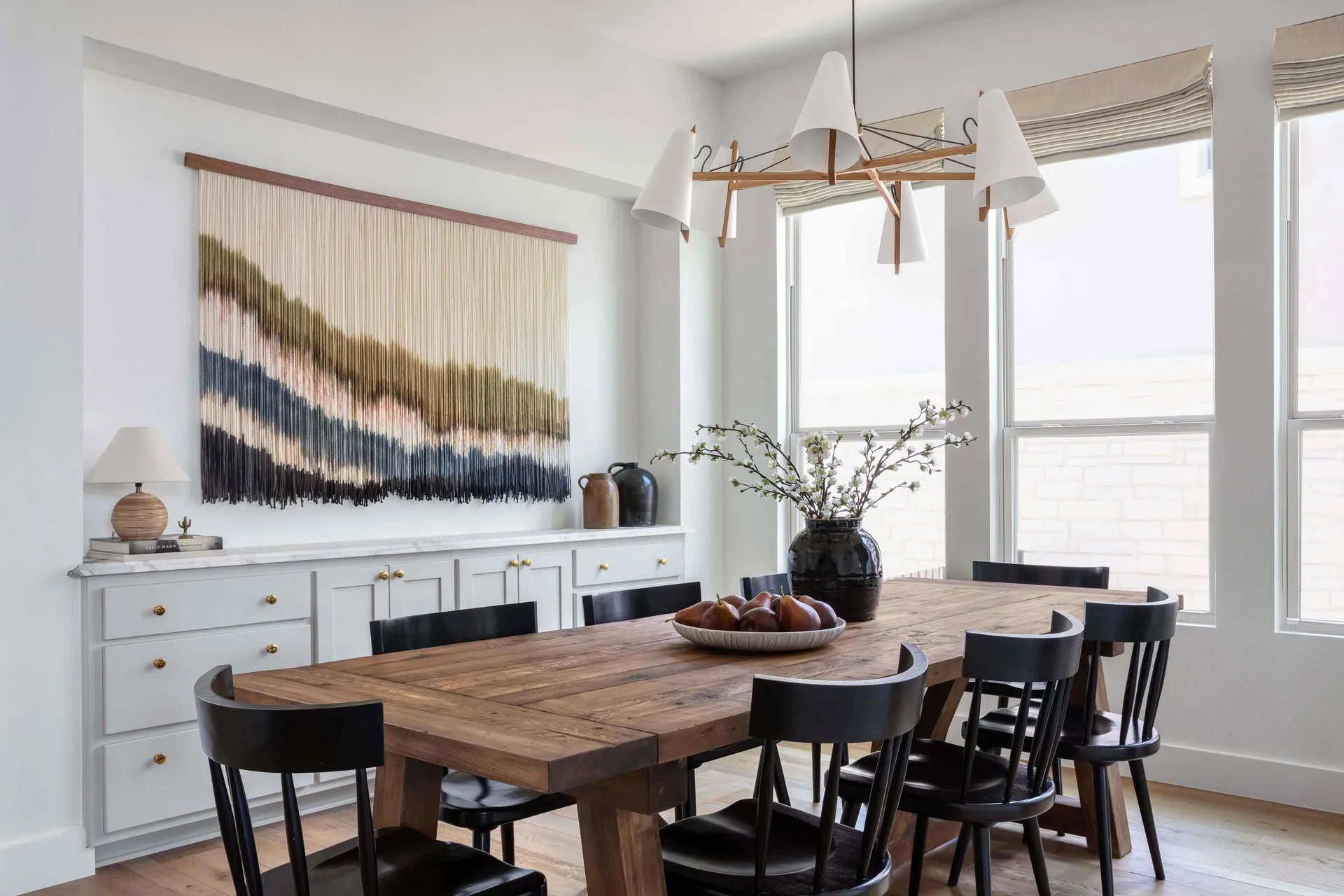 Dining room with large wooden table, built-in drawers and a large art piece made of hanging strings