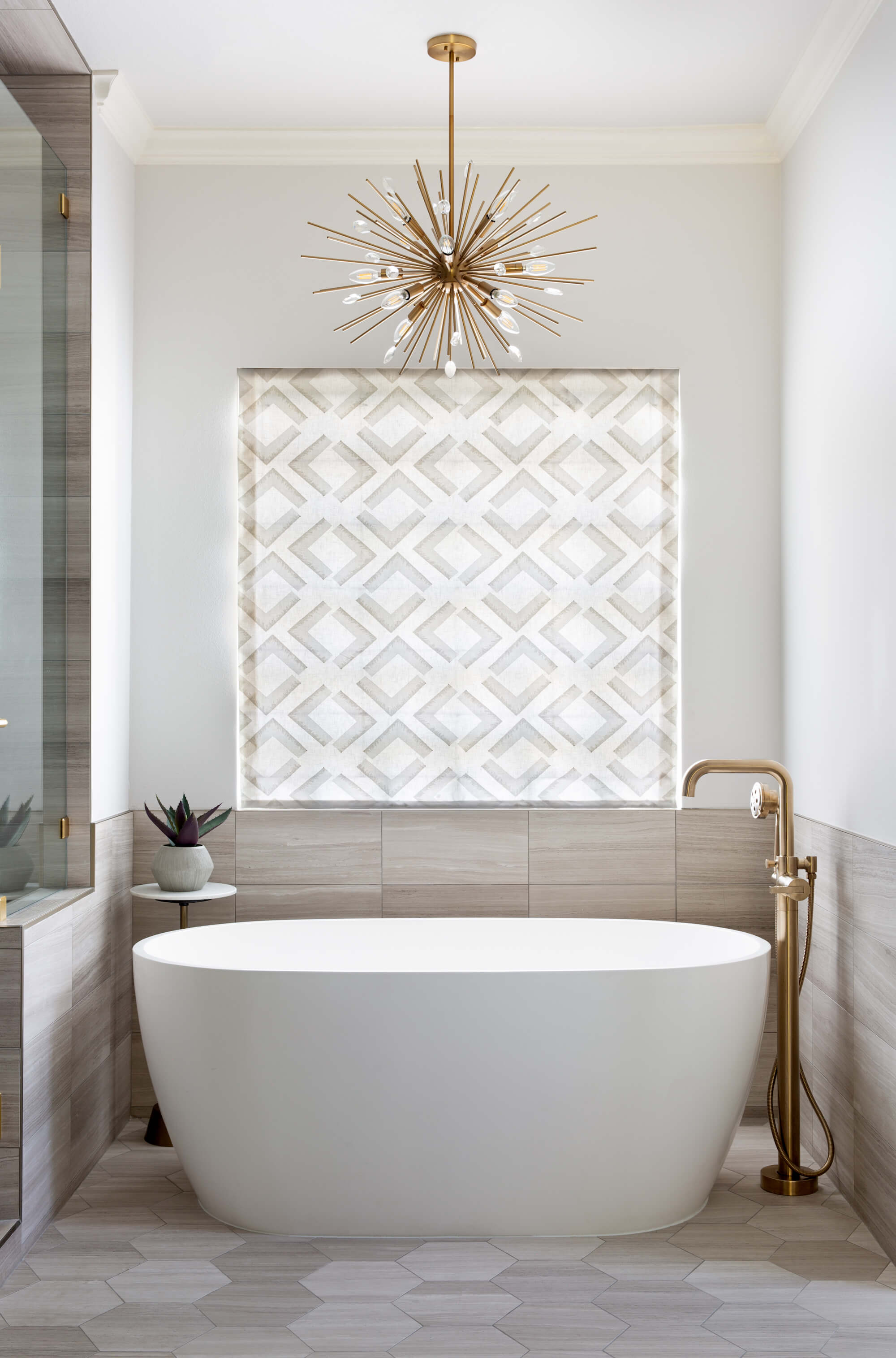 Bathroom with a free standing tub with a mid-century modern chandelier hanging above it