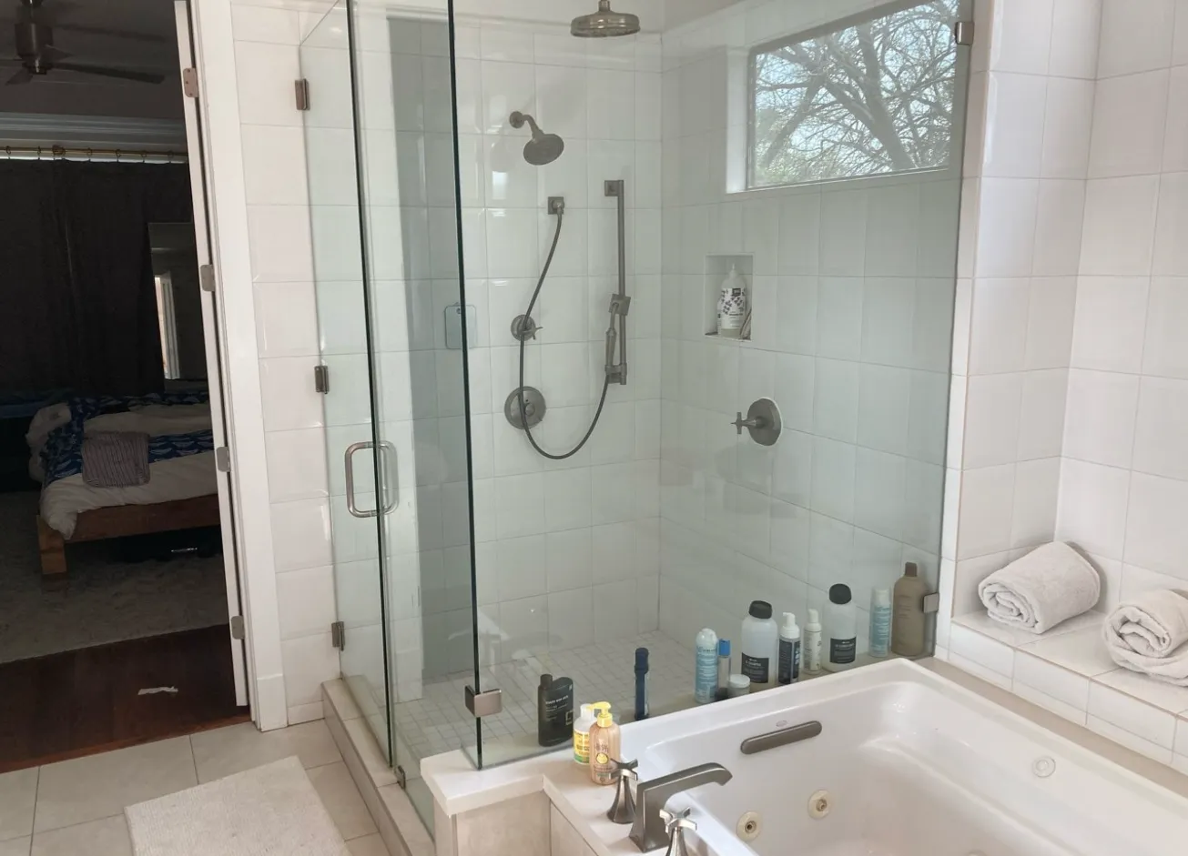 Bathroom with a white tiled standing shower and jetted tub