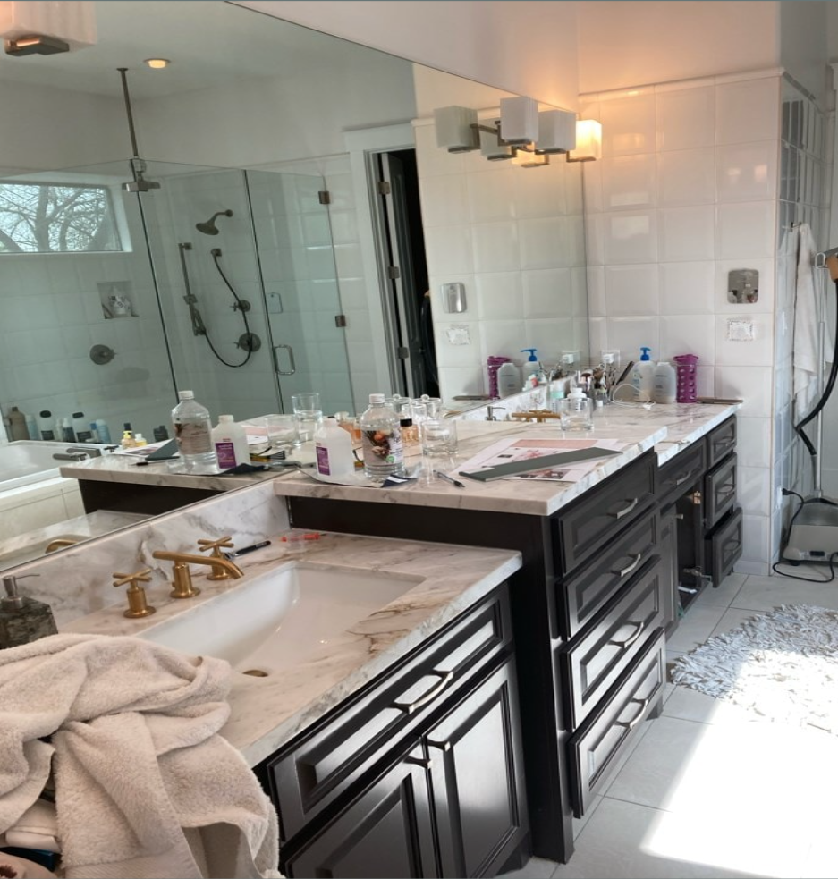 Bathroom with a double sing with dark cabinets and marble counters