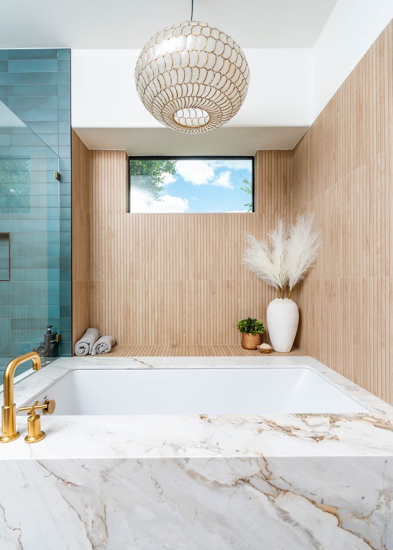 Large tube encased in marble with wood walls and a chandelier hanging above it