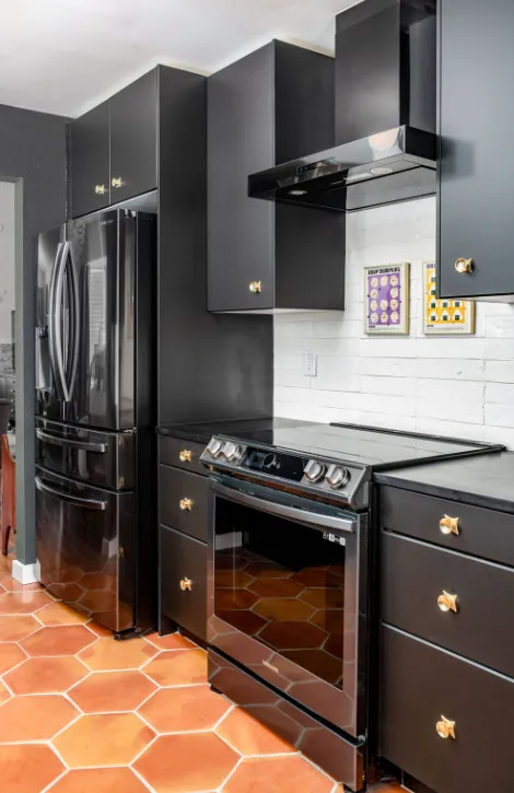 Galley style kitchen with terracotta hexagon tile flooring, dark blue cabinets, and white tile backsplash