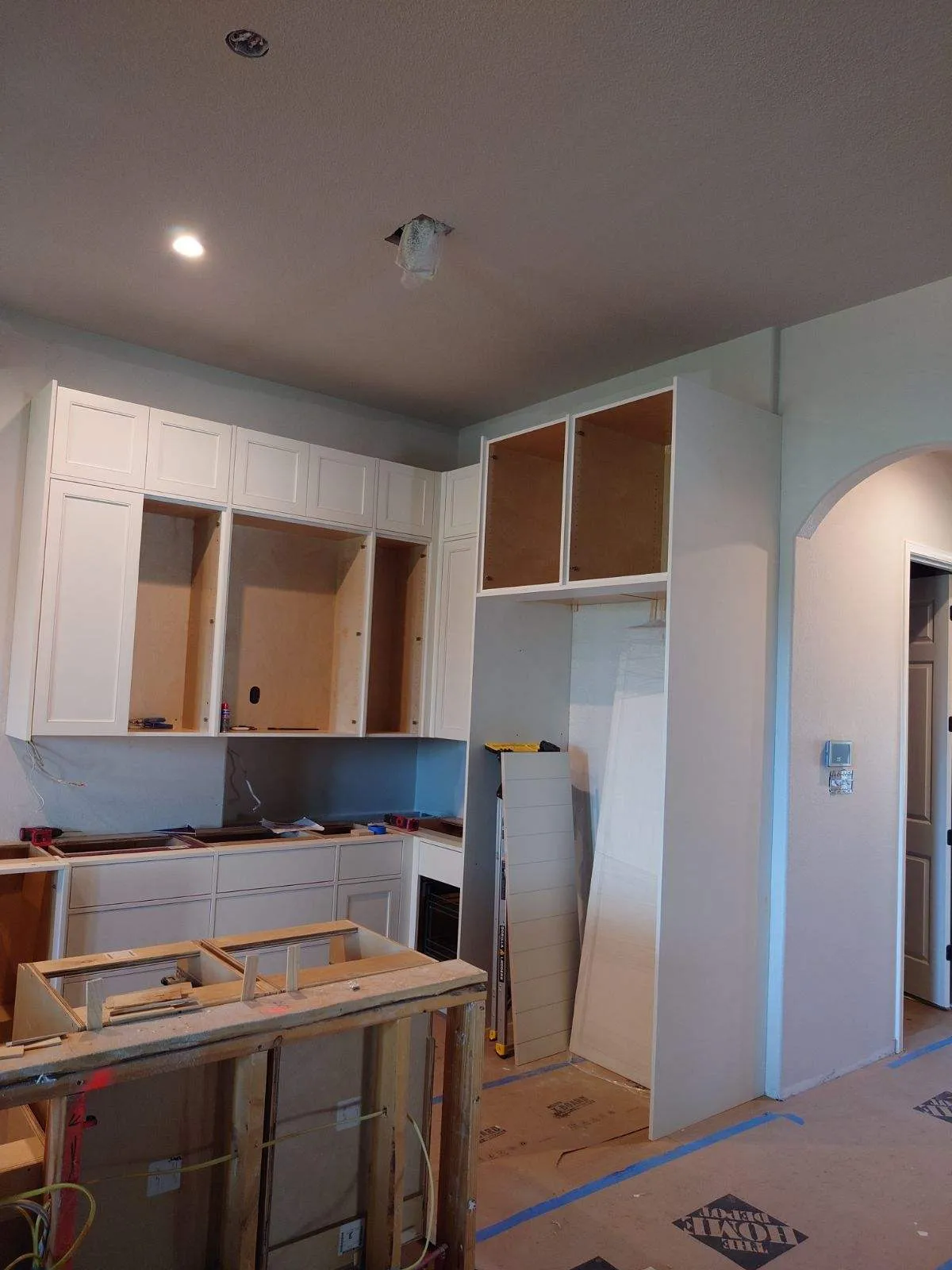 Partially installed white cabinets and construction tools for a kitchen remodeling in Austin.