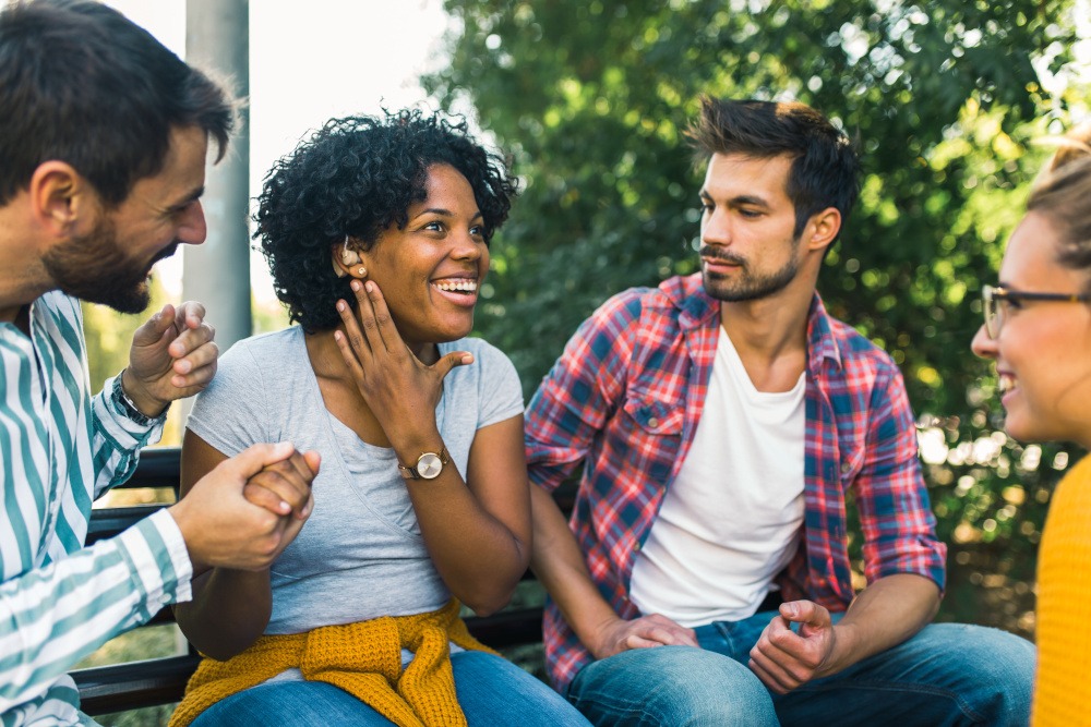 Friends surrounding their friend who is using her new hearing aid.