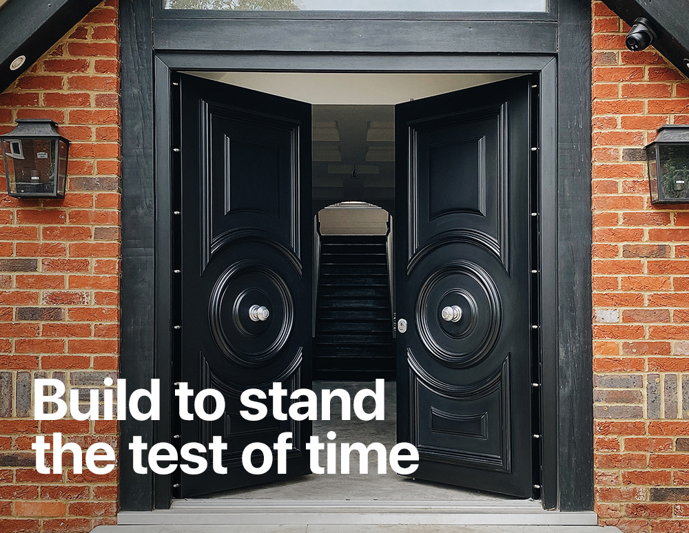Open black double security doors with circular decorative panels set in a brick entrance, with the text “Built to stand the test of time.”