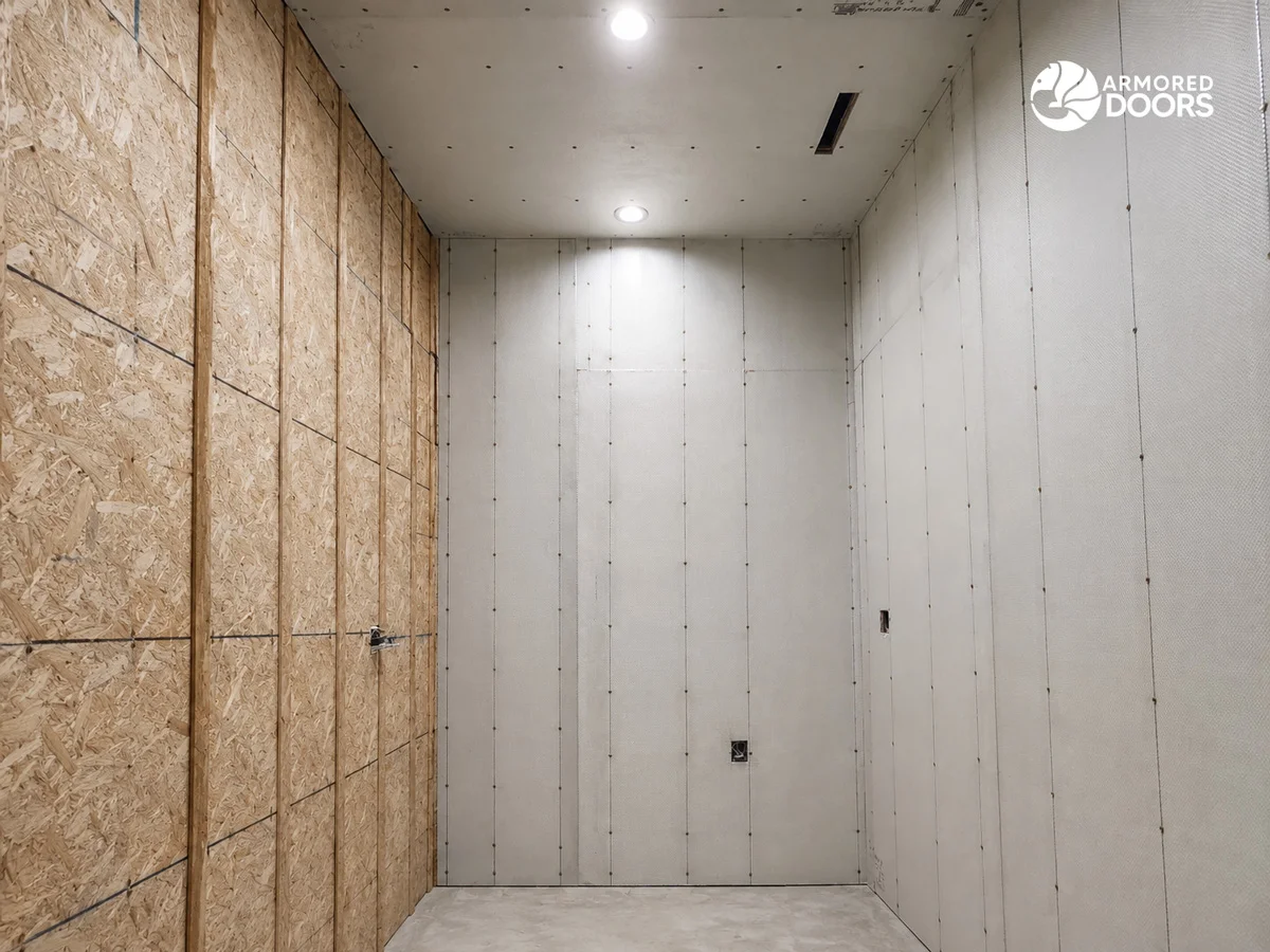 Safe room under construction with Armored Doors ballistic fiberglass panels fastened across the walls and ceiling beside wood wall sheathing.