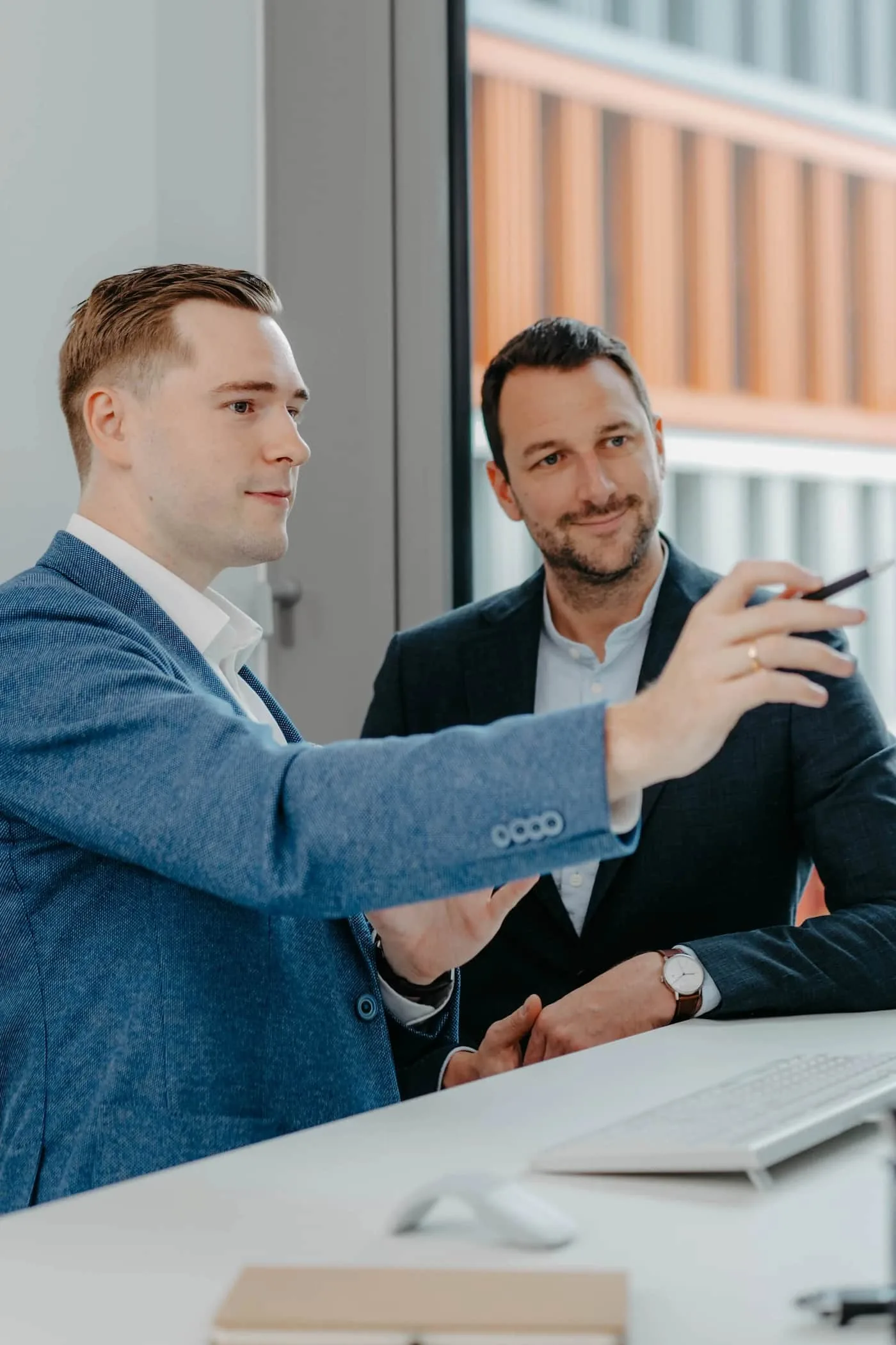 VAP Business Meeting: Zwei Maenner in Anzuegen diskutieren im Buero