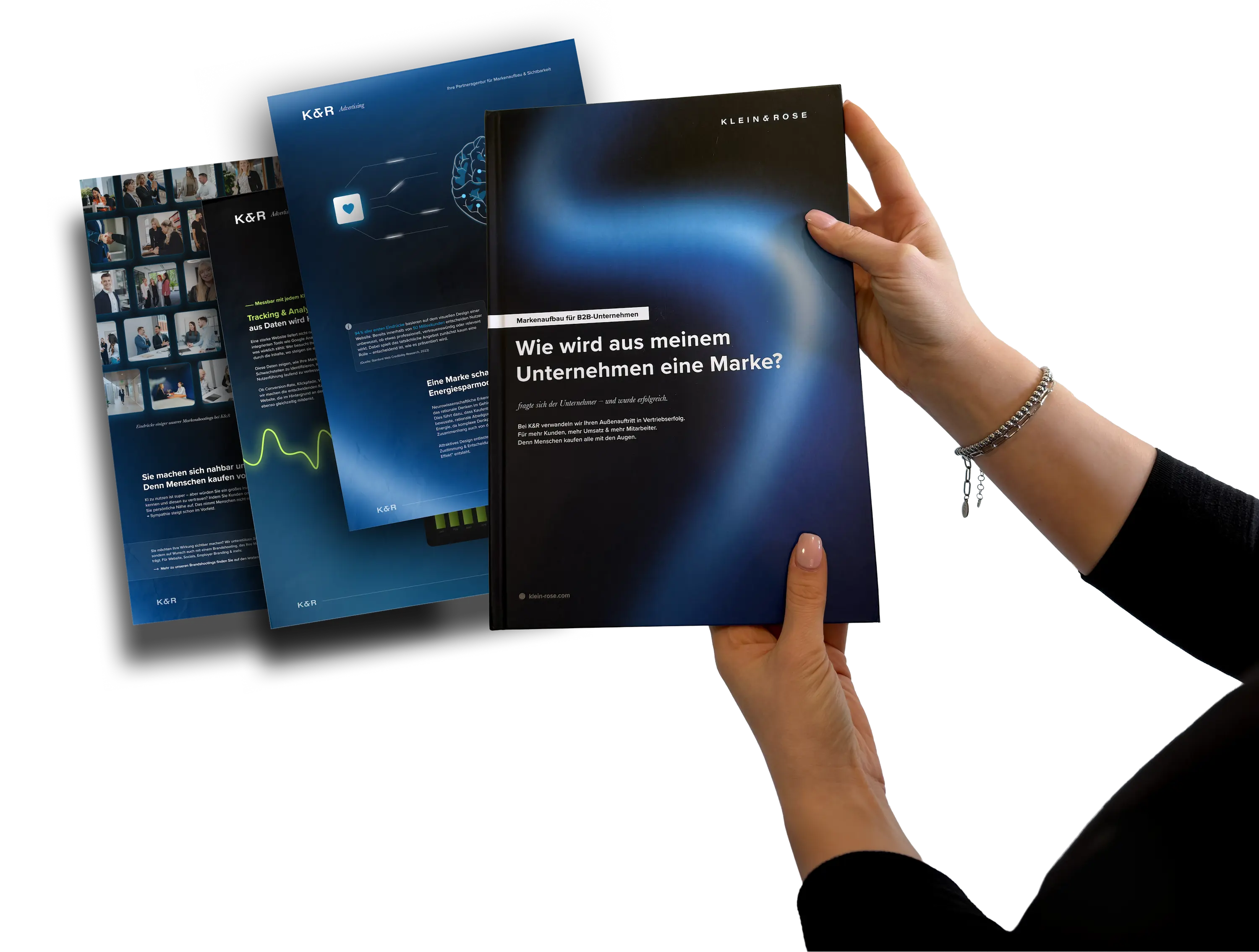Haende halten K&R Markenhandbuch, Tablets mit Website-Designs im Hintergrund