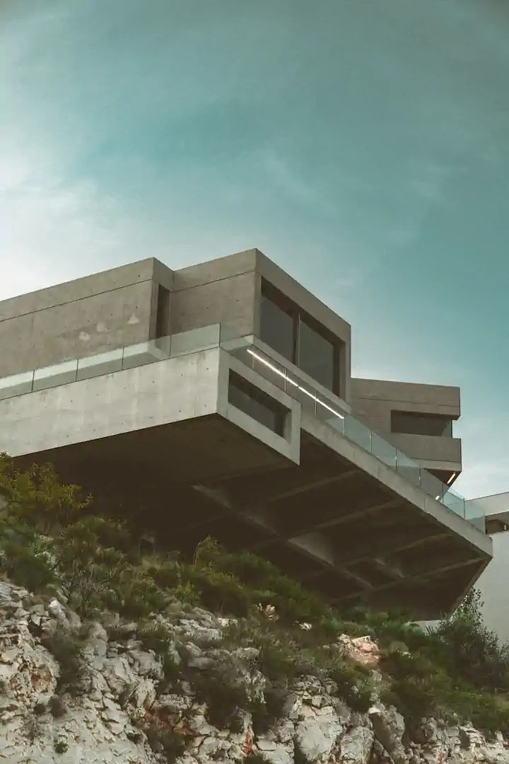 Kragarm-Betonvilla auf Felsklippe vor türkisblauem Himmel – Architekturprojekt Mittelmeer