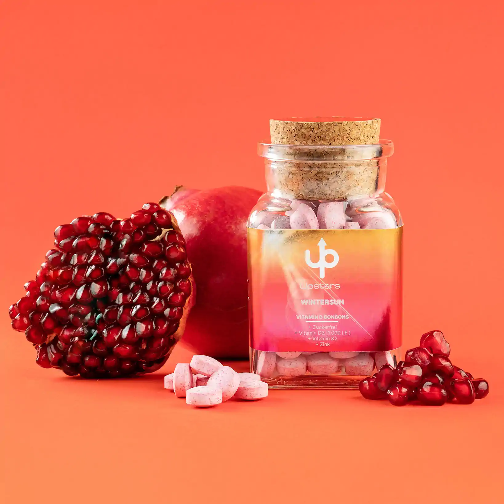 Upsters Wintersun Glasflasche mit rosa Bonbons, Granatapfel und Kernen auf Orange – Upsters Wintersun
