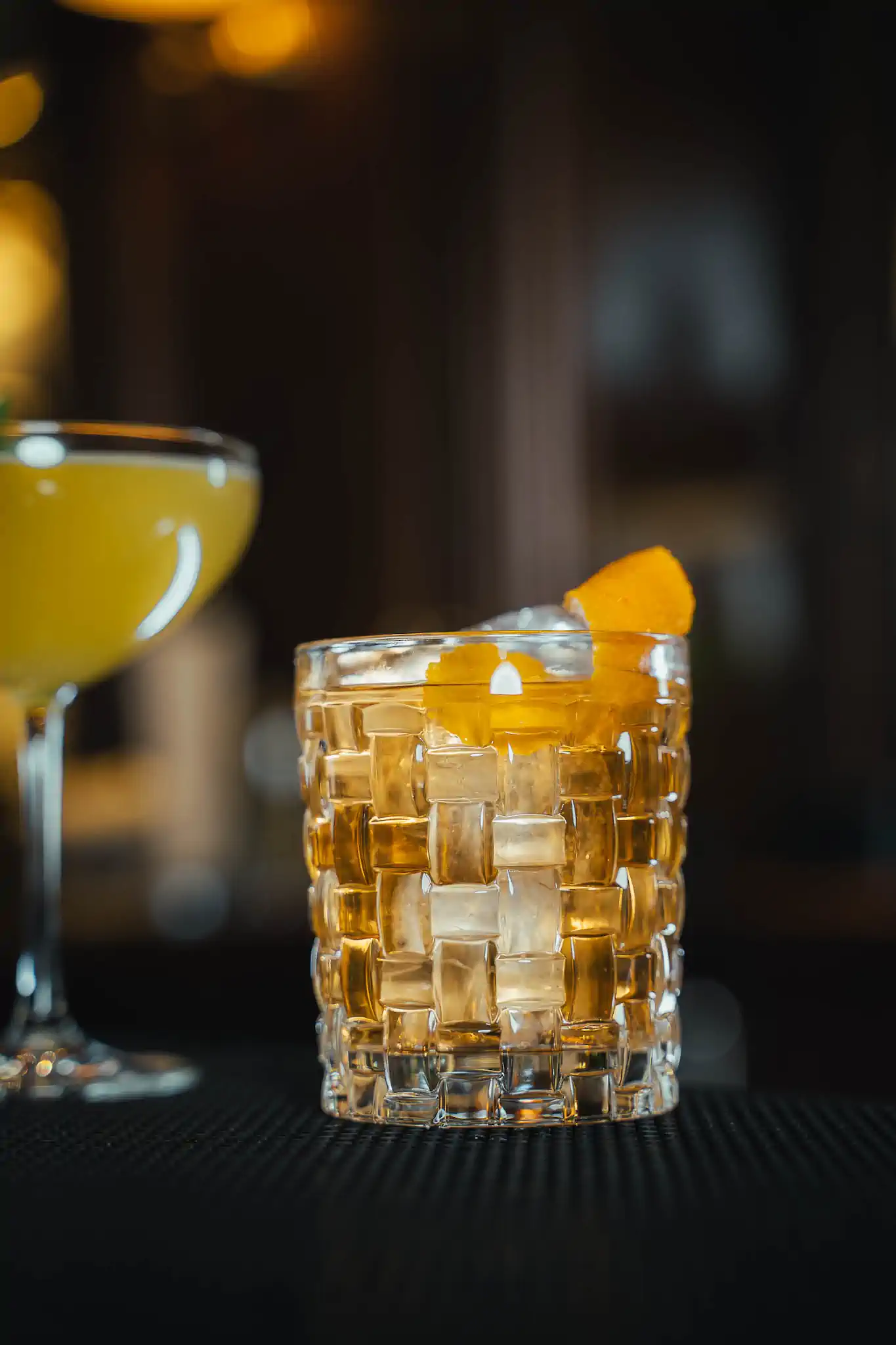 Old Fashioned mit Orangenzeste in geflochtenem Kristallglas auf Barmatte – Steigenberger Frankfurter Hof