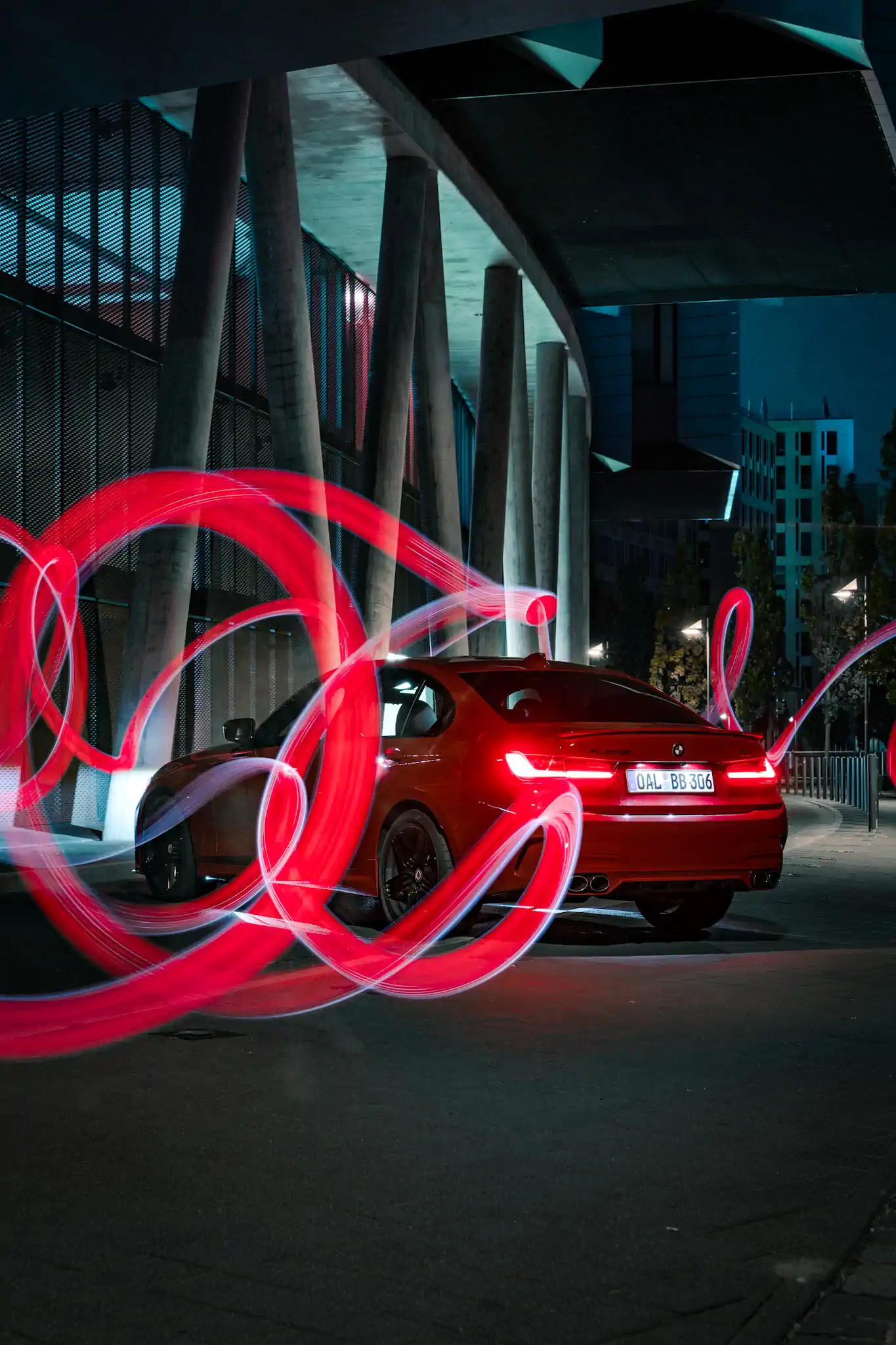 Roter BMW Alpina bei Nacht unter Betonstützen mit roten Lichtmalerei-Kreisen – Euler Alpina Days