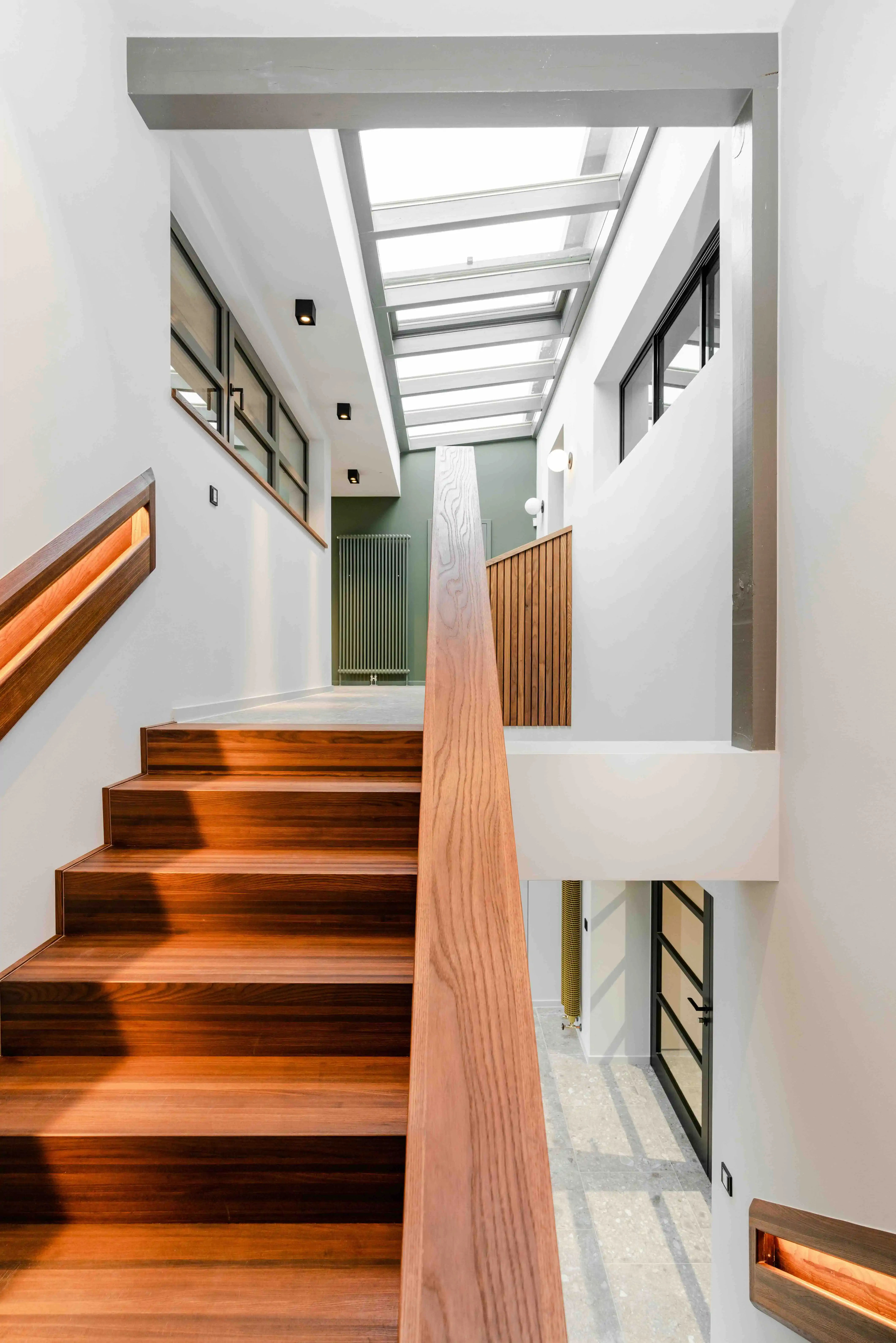 Modernes Treppenhaus mit Holzstufen, Glasdach und grüner Akzentwand – Fyrnys Architekturvisualisierung