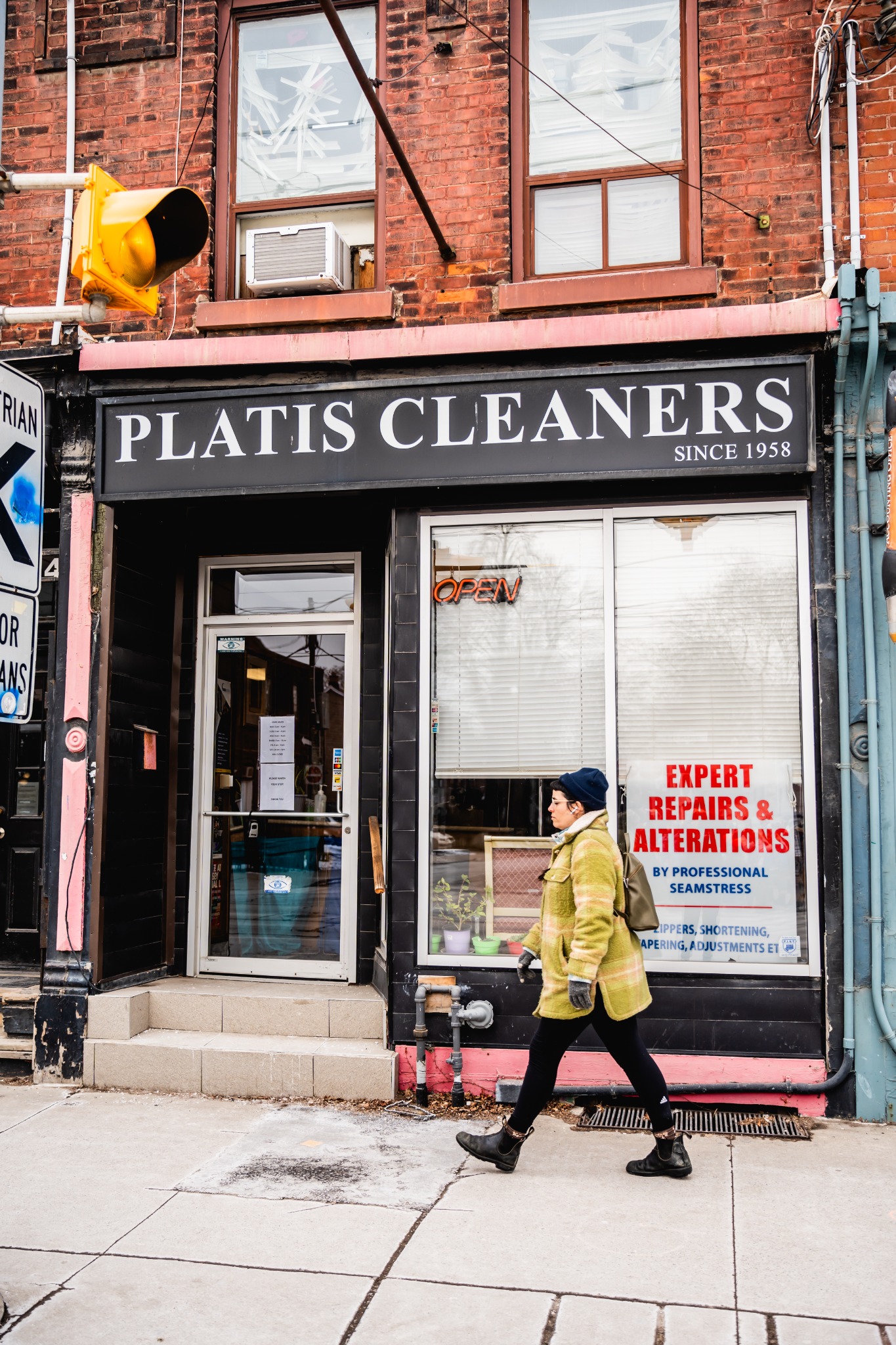 A customer walking past a Platis Cleaners storefront in Toronto