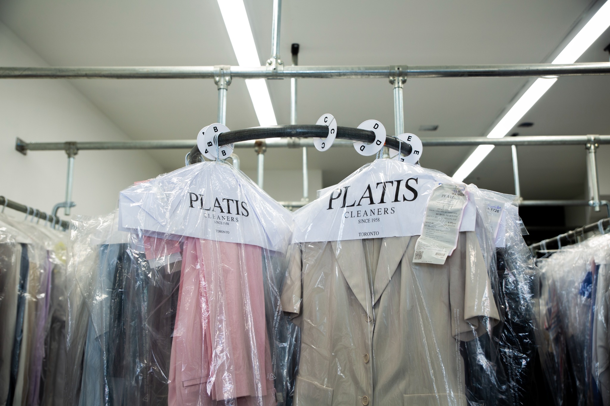 Garments in Platis Cleaners protective covers hanging in the cleaning facility.